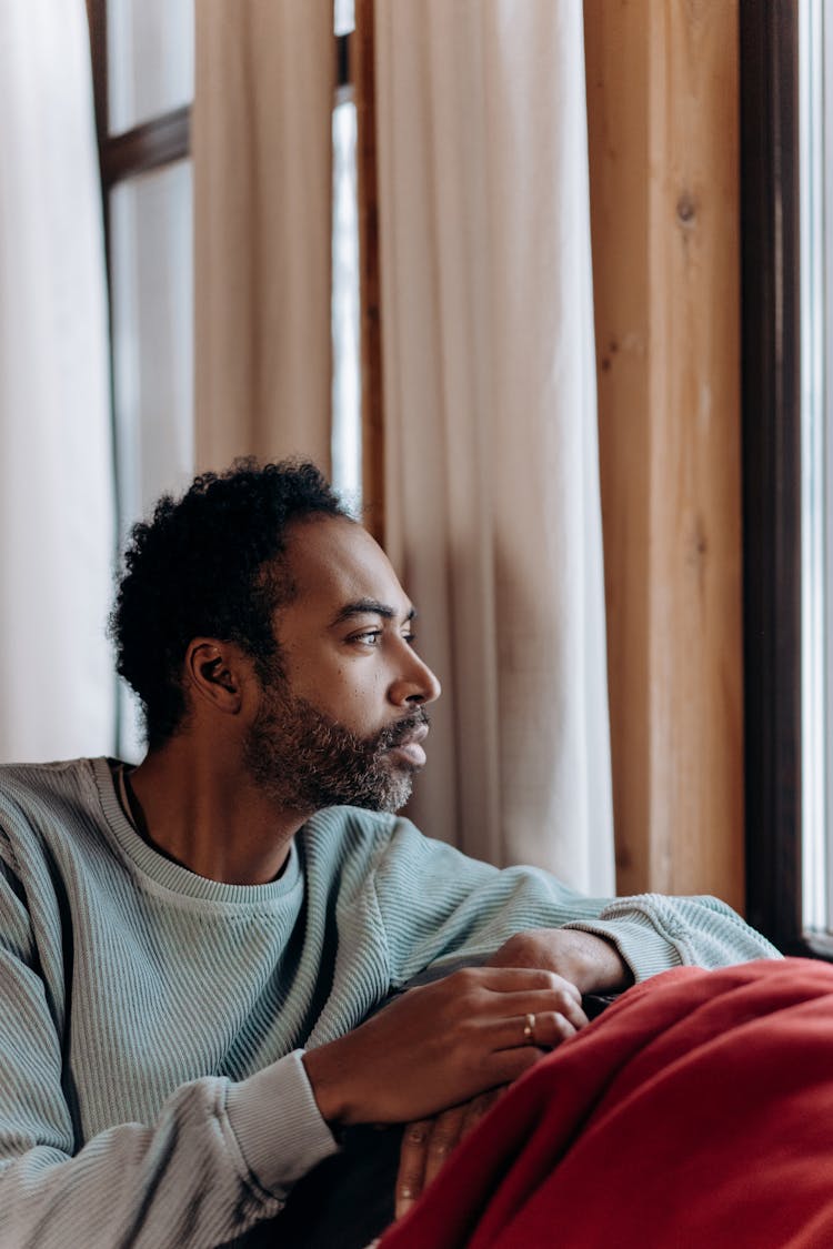 A Man Sitting On A Sofa By A Window