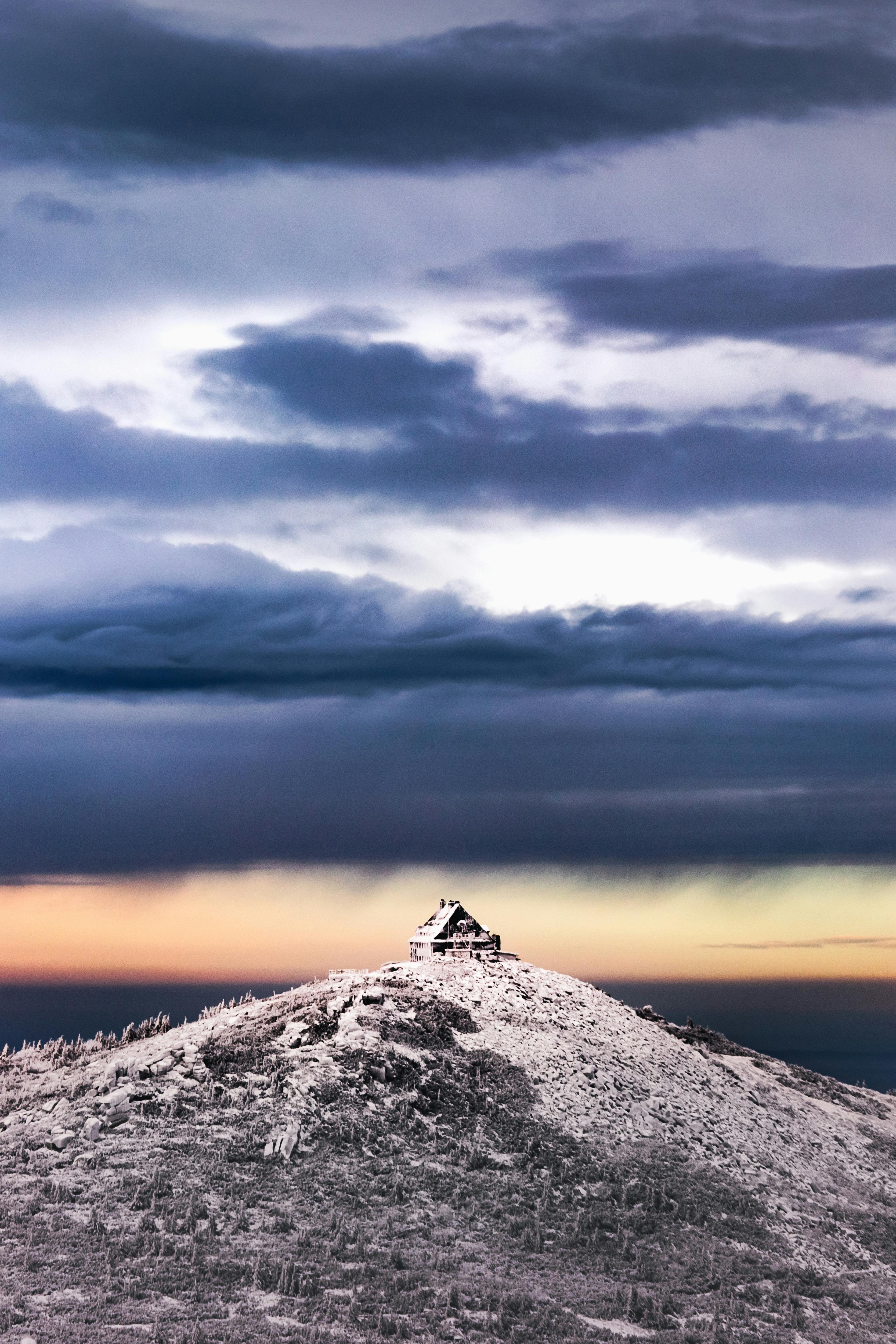 Prescription Goggle Inserts - A dramatic winter landscape with a solitary cabin atop a snow-covered hill under a moody sky.