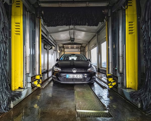 Automatic car wash with spinning brushes dragging across vehicle paint surface