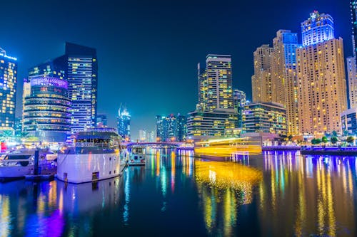 Free White Boat on Water Near City Buildings during Night Time Stock Photo