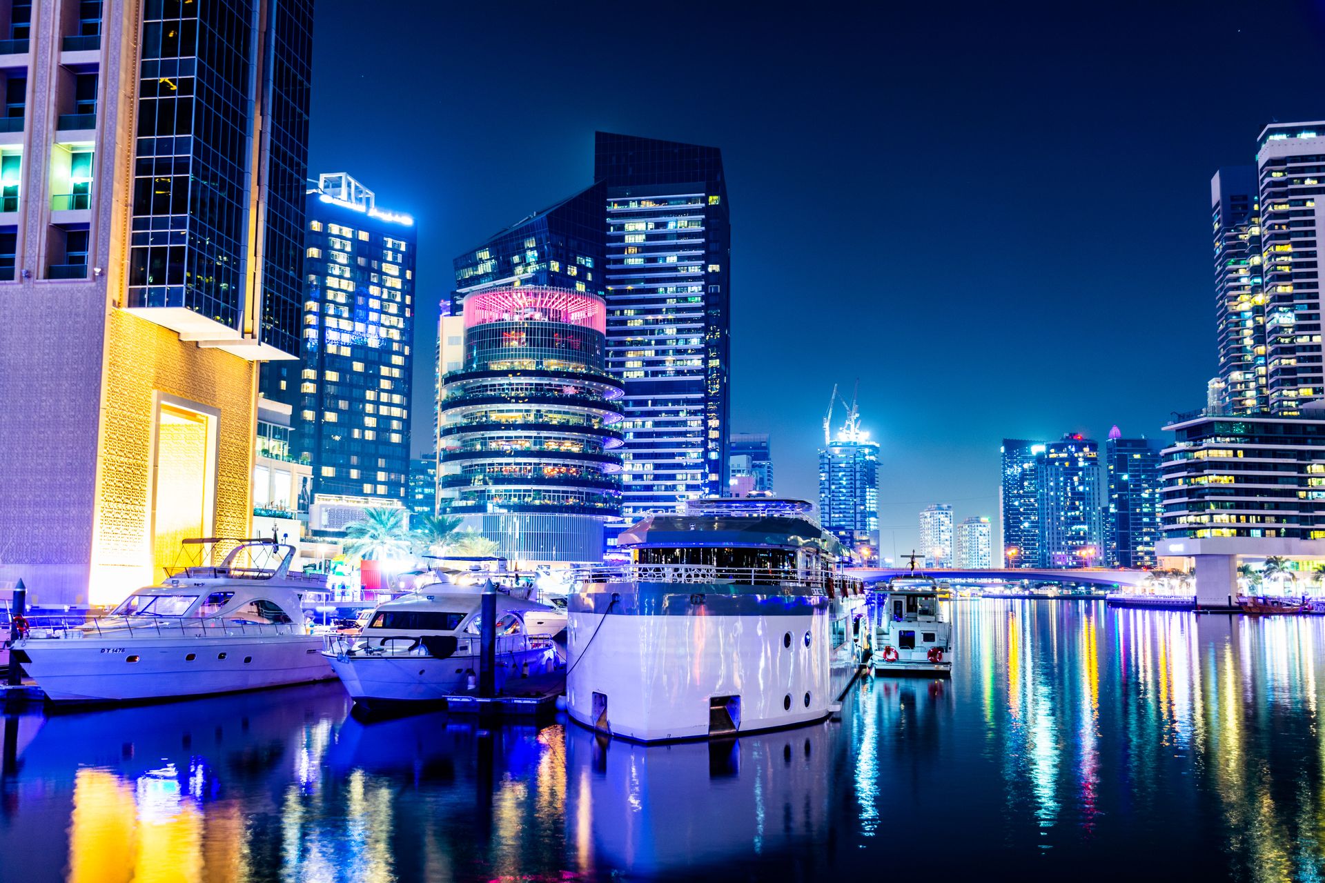 Stunning view of Dubai Marina at night, showcasing illuminated skyscrapers and yachts.