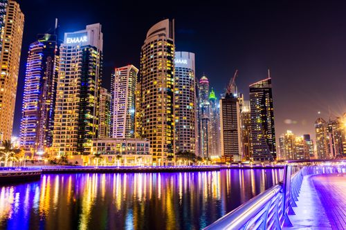 Free Vibrant nighttime view of Dubai Marina's illuminated skyscrapers reflecting over the waterfront. Stock Photo