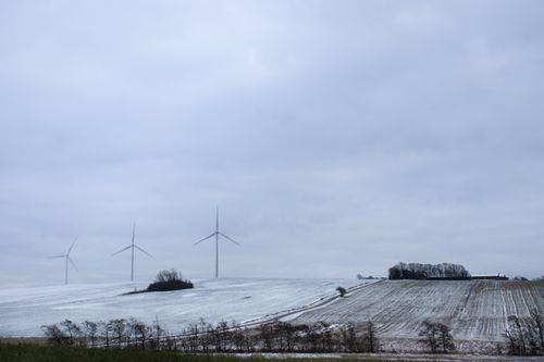 Free A serene snowy landscape in Randers, Denmark, featuring wind turbines under a cloudy sky. Stock Photo
