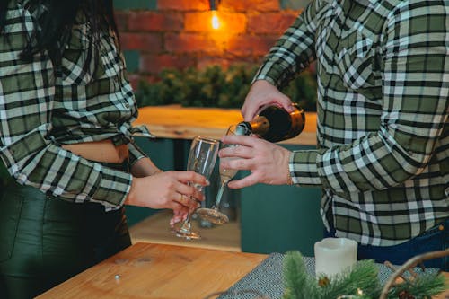 Crop couple pouring champagne in wineglasses