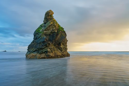 Free Captivating sea stack in tranquil ocean against a colorful sunset sky. Stock Photo