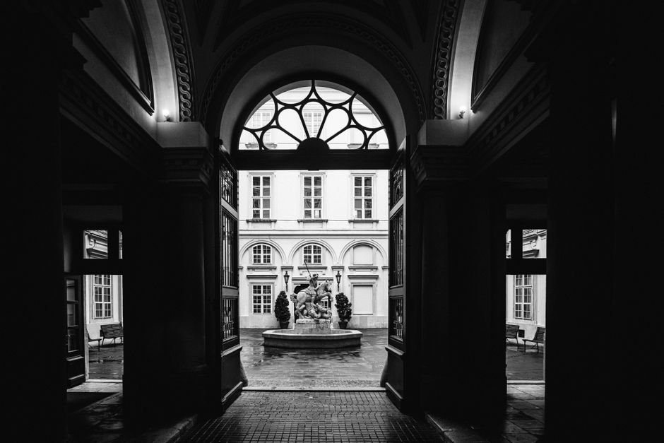 Elegant courtyard in Bratislava featuring an ornate fountain, captured in black and white.