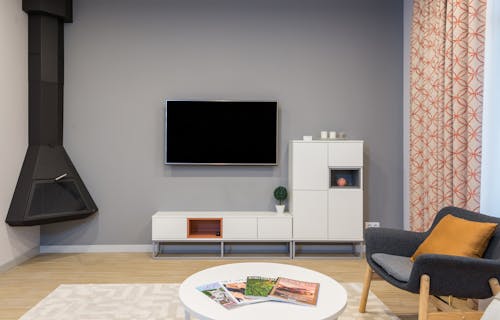Free Modern TV and fireplace hanging on wall in minimalist apartment with white furniture and comfortable armchair Stock Photo