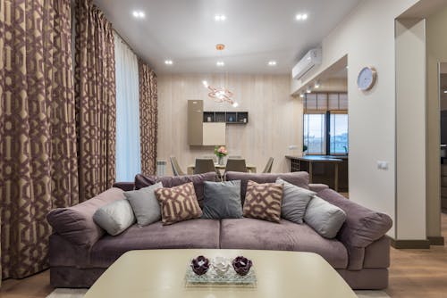 Free Soft comfortable couch with various cushions and coffee table placed in cozy living room with dining zone Stock Photo