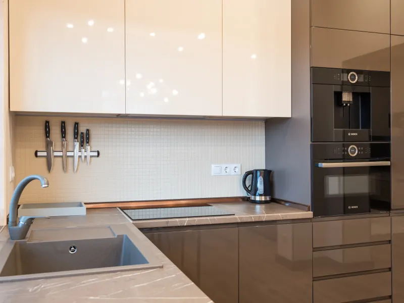 Light apartment kitchen with glossy minimalist furniture and modern appliances Light apartment kitchen with glossy minimalist furniture and modern appliances