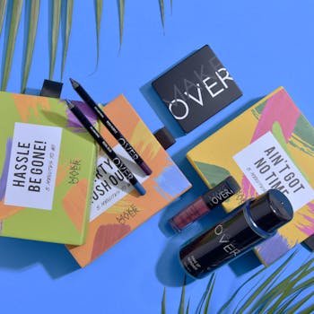 Vibrant makeup set with palettes and eyeliners on a trendy blue surface.