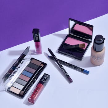 Flat lay of various makeup products on a stylish purple background. Ideal for beauty promotions.