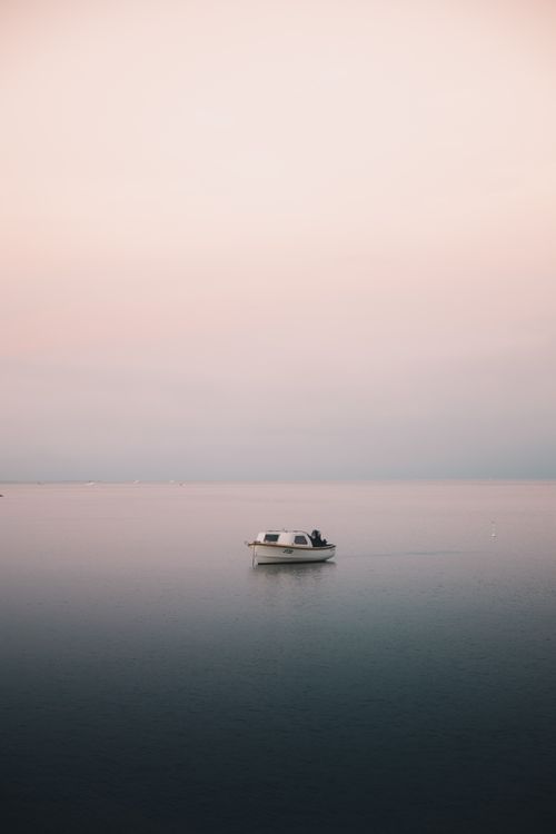 Free A tranquil scene with a small boat on calm waters under a pastel sky during dusk in Australia. Stock Photo
