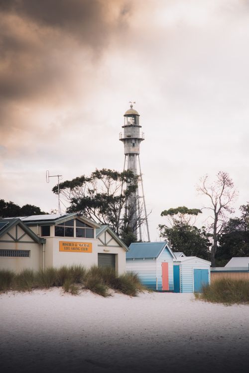 Free A serene view of McCrae Beach lighthouse and surrounding houses at dusk, Australia. Stock Photo
