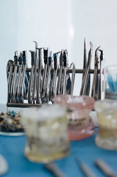 A set of stainless steel dental tools displayed on a blue surface in a clinic setting.