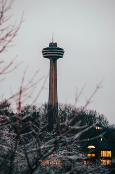 The Skylon Tower stands prominently against a winter backdrop with leafless trees and glowing lights at twilight.