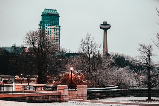 A picturesque winter cityscape featuring Skylon Tower amid bare trees in Canada.