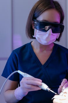 Female dentist wearing eyewear and face mask during dental procedure, ensuring safety.