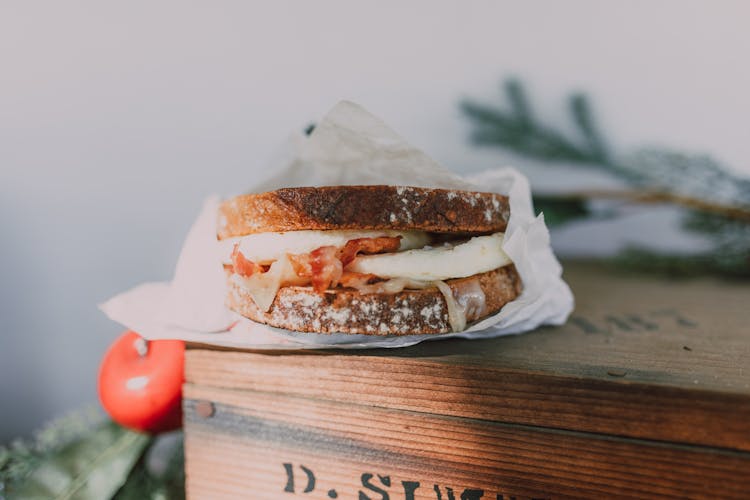 A Bacon And Egg Sandwich Over A Wooden Box