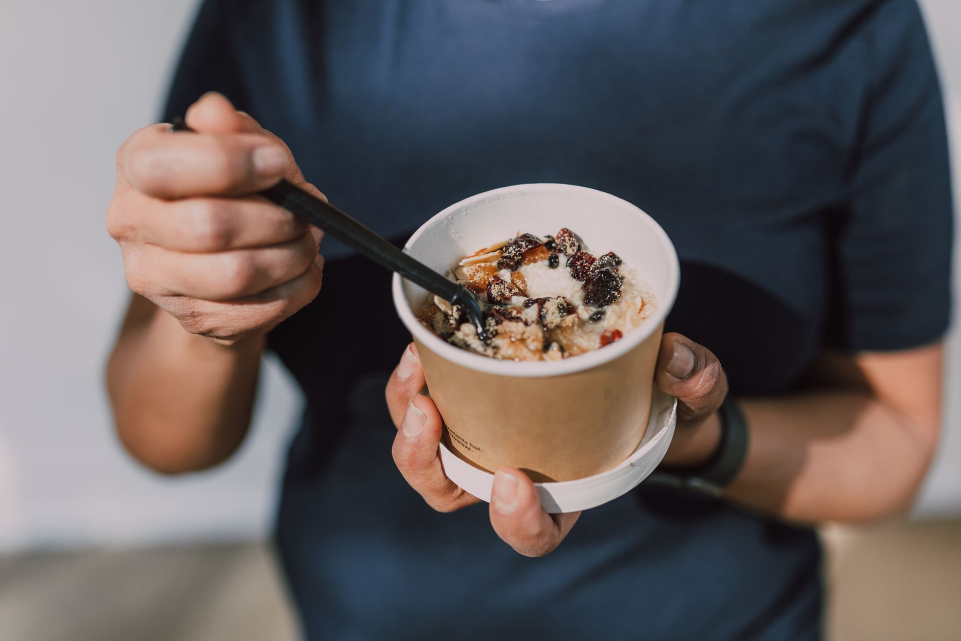 健康飲食與間歇性斷食的協作之道:提升健康的實用指南 Hands holding a cup of vegan oatmeal with fruits and nuts, perfect for a healthy breakfast on the go.