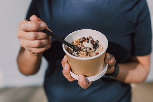 Hands holding a cup of vegan oatmeal with fruits and nuts, perfect for a healthy breakfast on the go.
