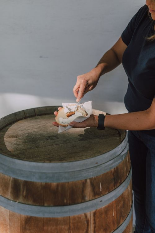 Free Close-up of a hand spreading cream cheese on a bagel over a wooden barrel. Stock Photo