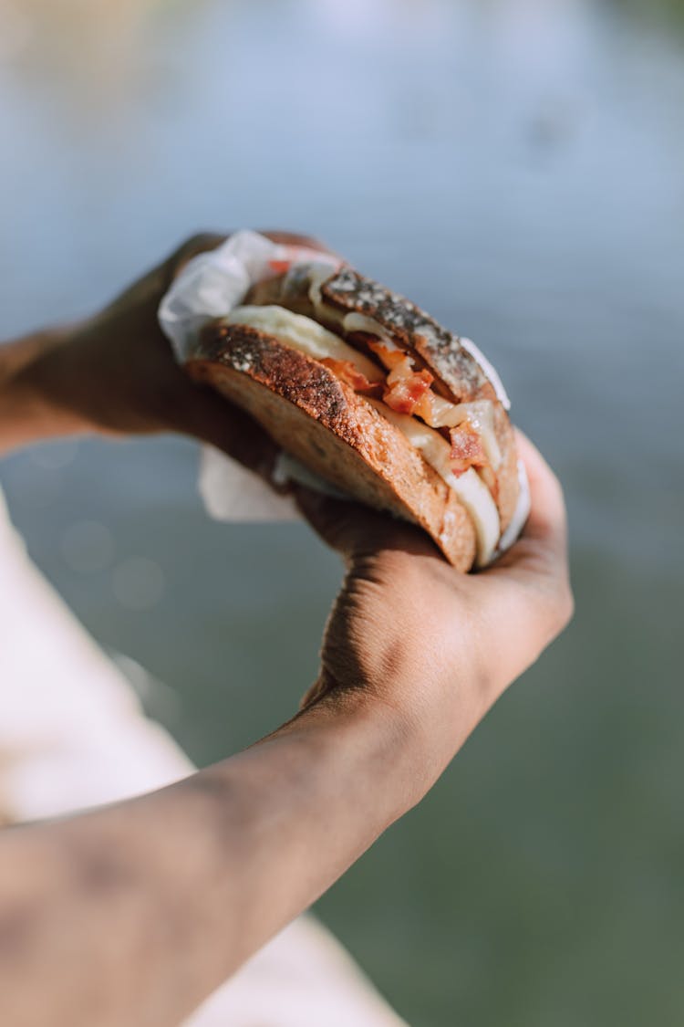 A Person Holding A Bacon And Egg Sandwich