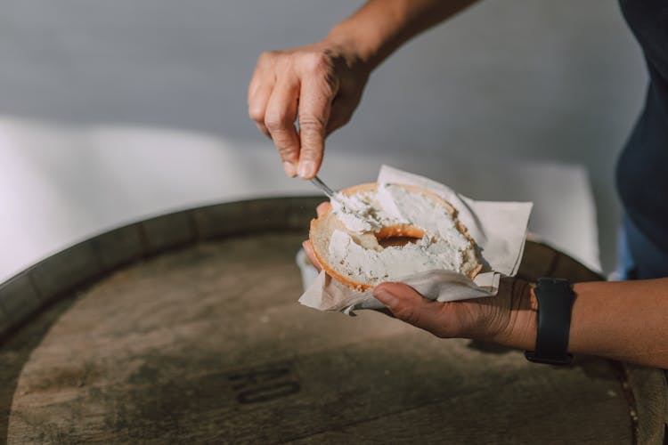 Spreading Cream Cheese On A Sliced Bagel