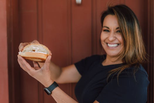 Woman enjoying a delicious cream cheese bagel, smiling happily.