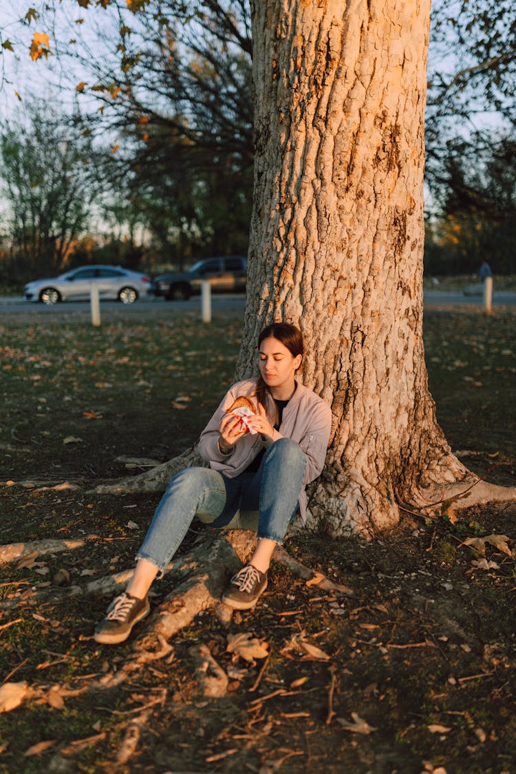 A Woman In The Park Eating A Sandwich