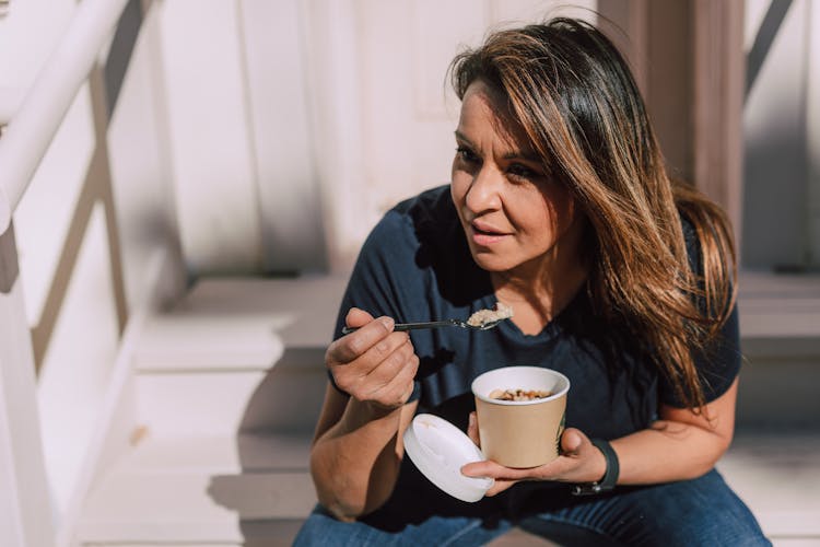 A Woman Eating A Bowl Of Oats