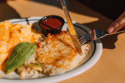 Tasty breakfast with hash browns, scrambled eggs, and avocado served on a sunny morning.