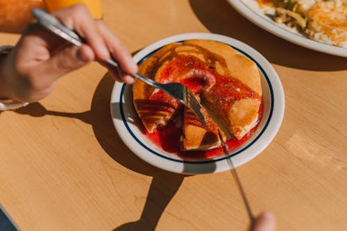 Free A Person Slicing Pancake on a Table Stock Photo