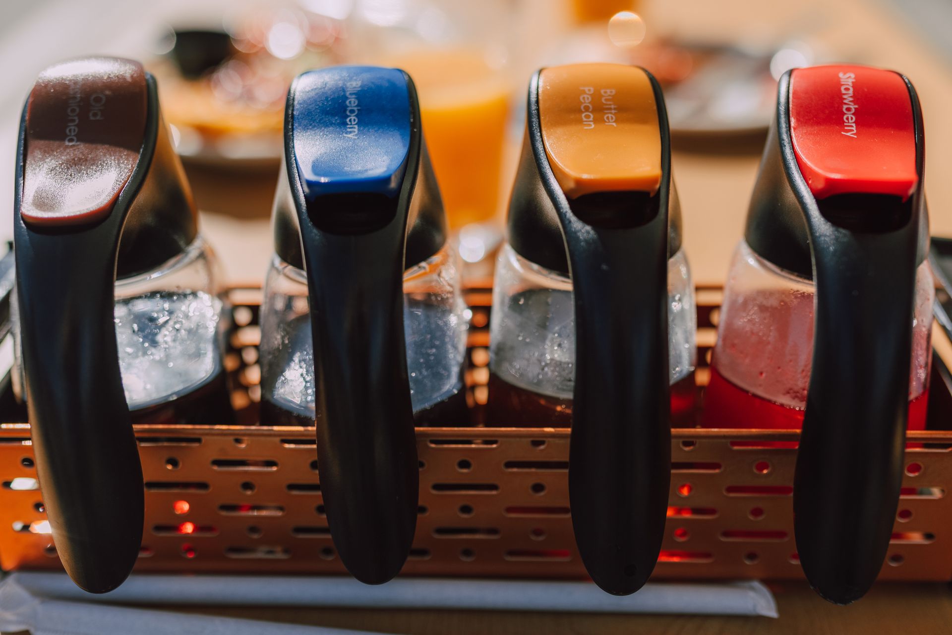 Close-up of assorted syrup bottles for breakfast, showcasing various flavors and colors.