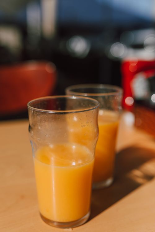 Free Close-up of two glasses filled with fresh orange juice on a sunny day, evoking a refreshing summer vibe. Stock Photo