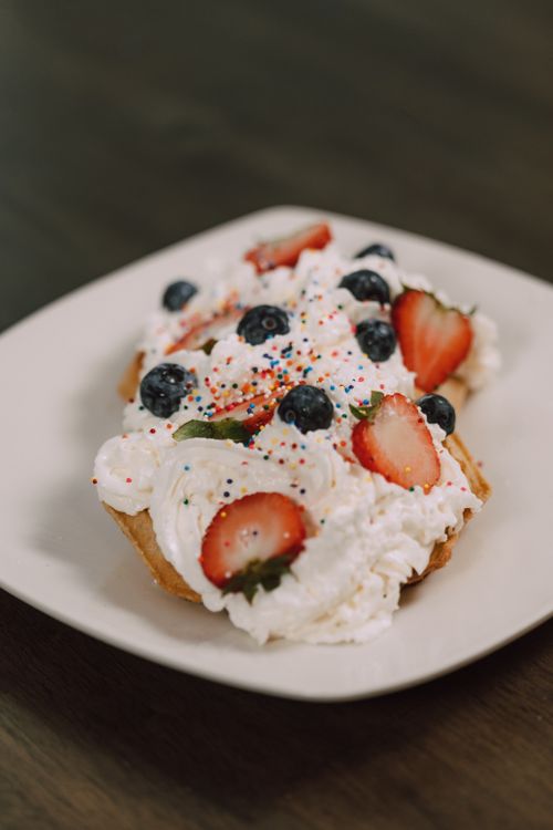 Free Delicious dessert with whipped cream, strawberries, and blueberries on a plate. Stock Photo
