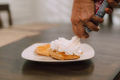 A Person Putting Whipped Cream on the Pancakes