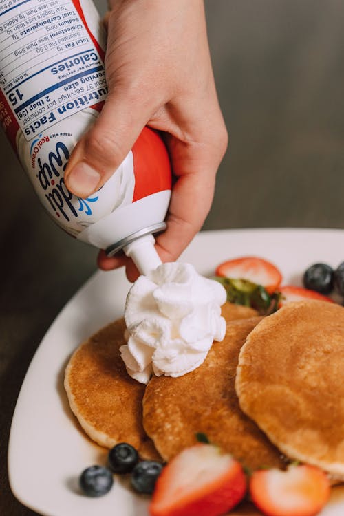 A Person Putting Whipped Cream on the Pancakes