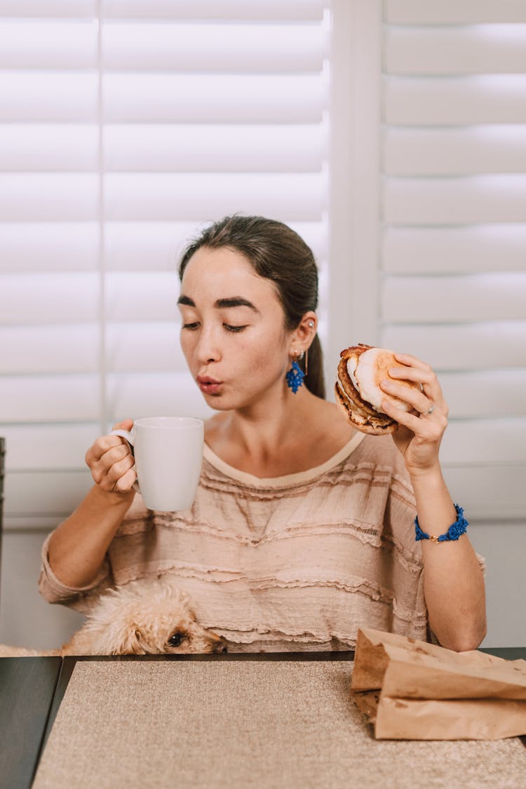 A Woman Holding Mug And Burger