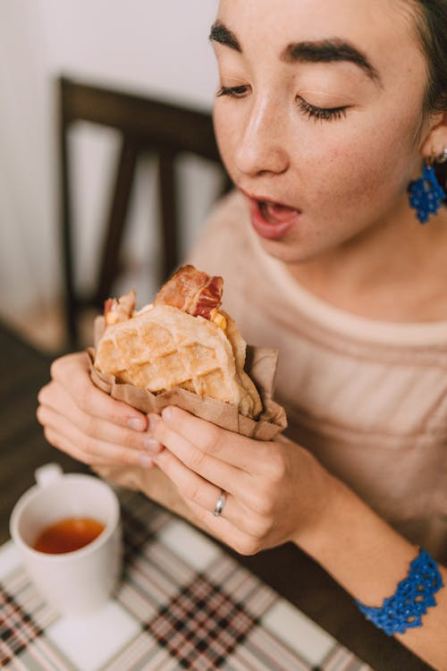 Woman Eating Waffle Bacon Sandwich