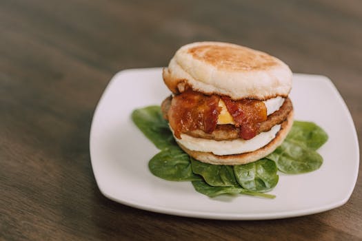 Tasty bacon and egg sandwich on a plate with fresh spinach garnish.