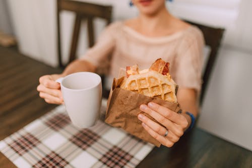Free Person holding a Waffle Sandwich and a Ceramic Mug  Stock Photo