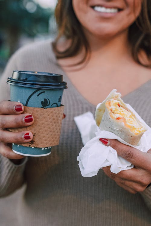 Free A Person Holding Cup of a Coffee and Sandwich Stock Photo