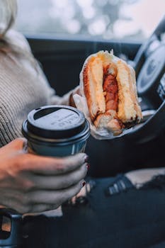 Enjoy a breakfast sandwich with coffee in the car, perfect for on-the-go mornings.