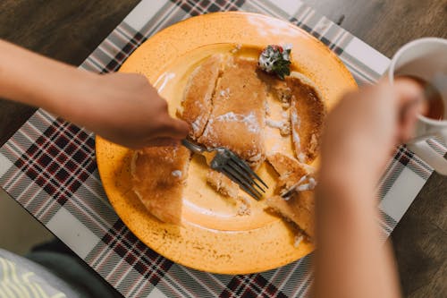 Free Person Holding Fork and Bread Knife on Yellow Plate Stock Photo