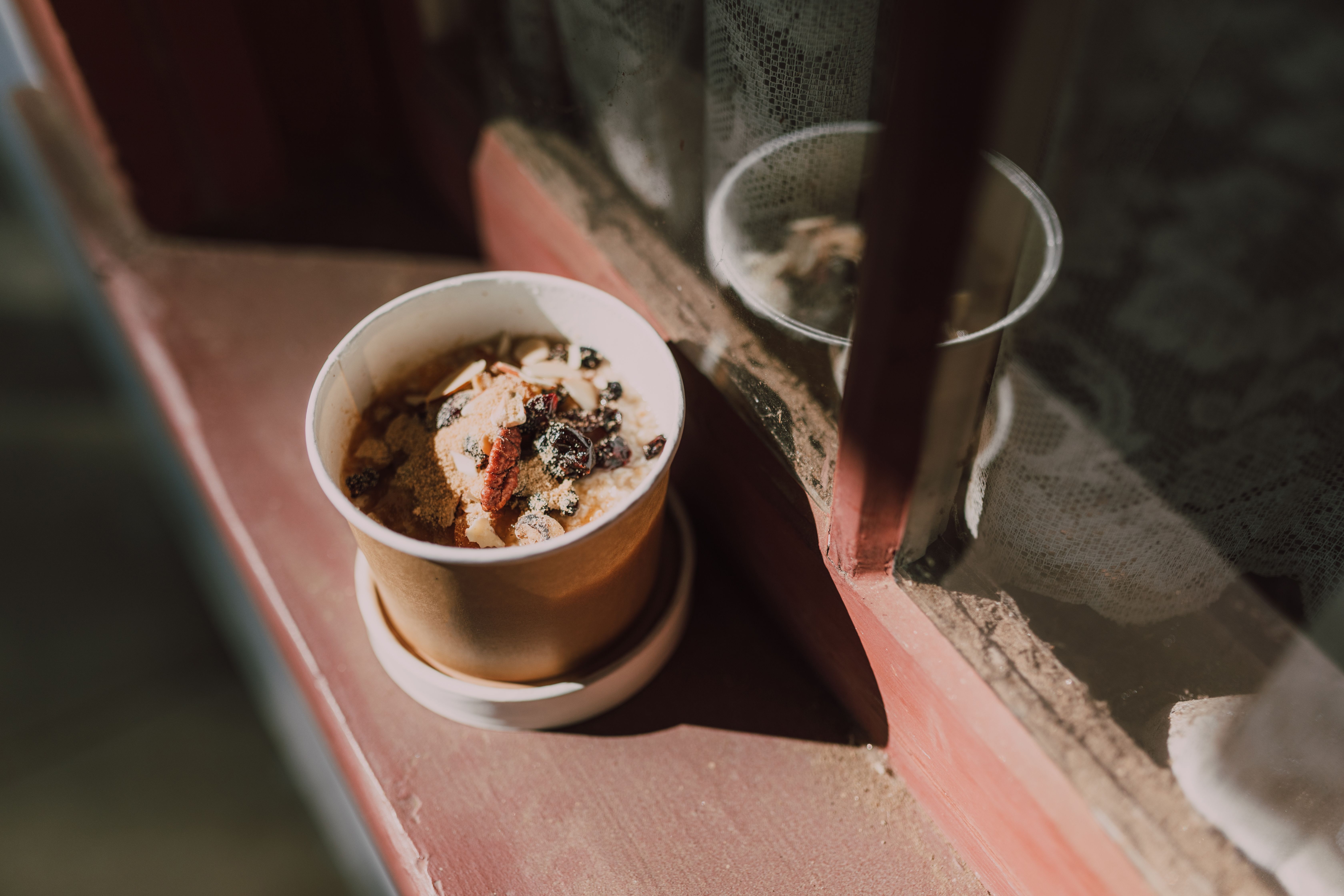 A warm bowl of oatmeal with fruits and nuts by the window, capturing morning light.