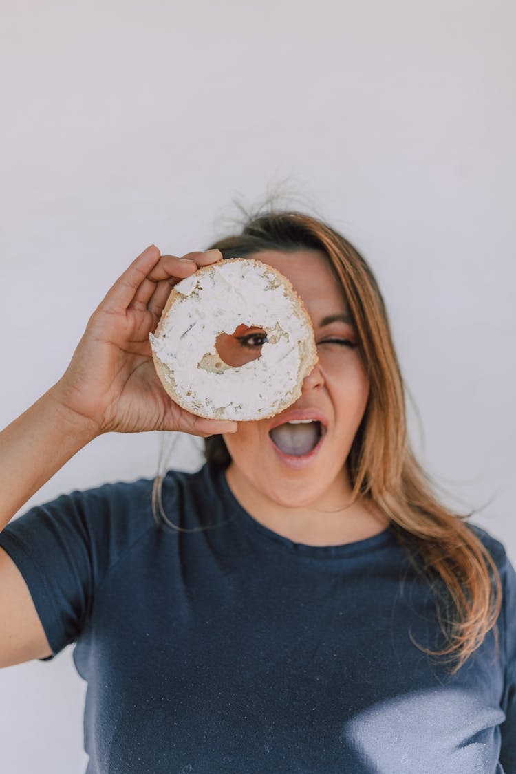 Woman Holding A Sliced Bagel With Cream Cheese