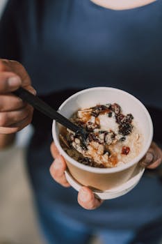 Healthy oatmeal bowl with berries and nuts held by a person. Perfect for breakfast inspiration.