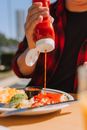 A Person Pouring Catsup on Food