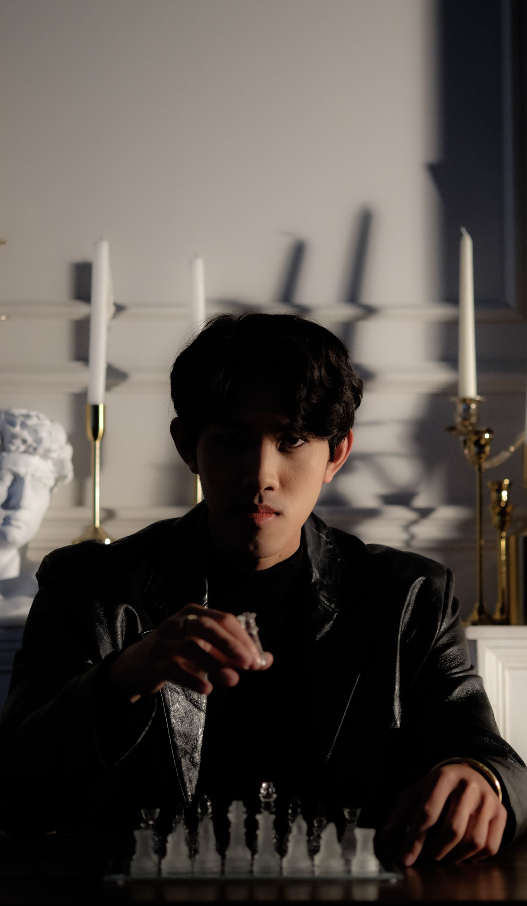 Young man playing chess in low light setting, evoking a dramatic ambiance.
