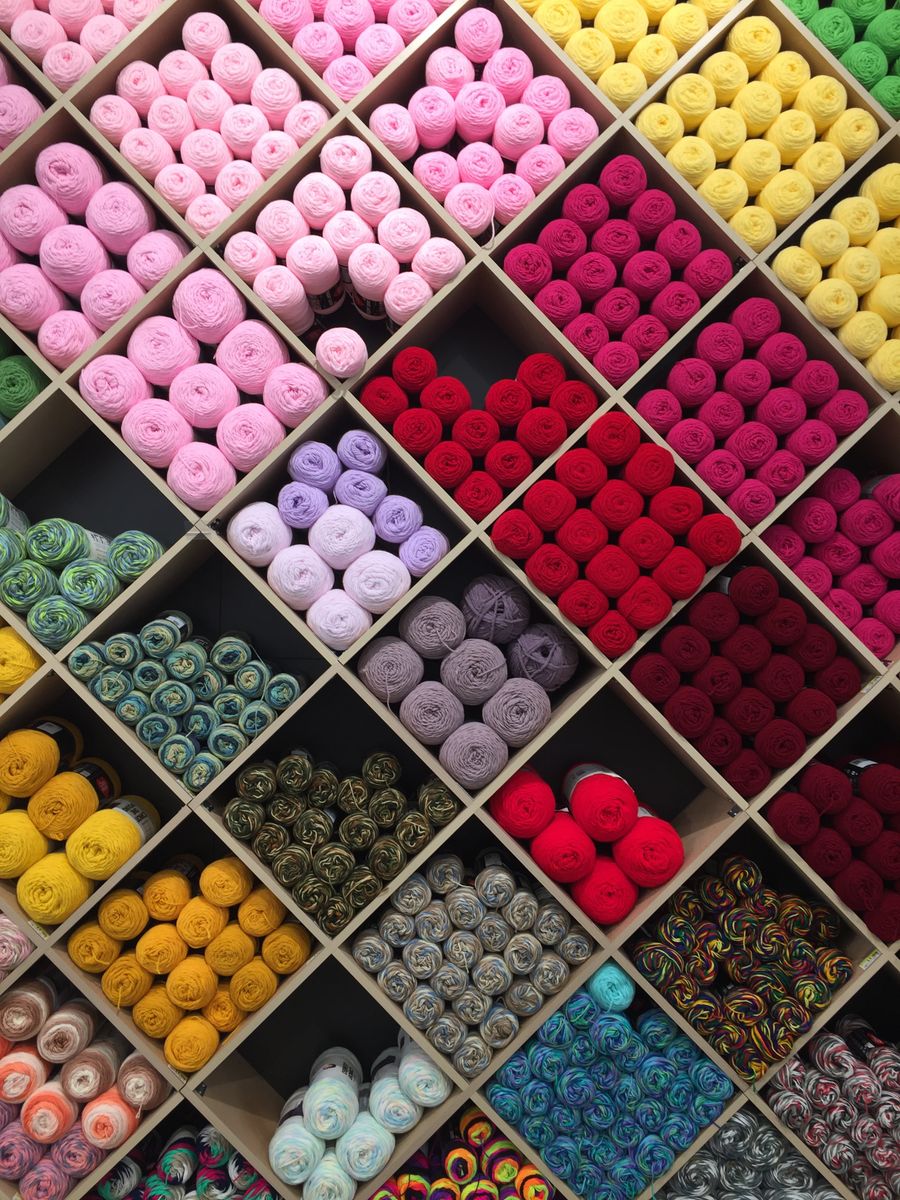 A grid of yarn in many colours organised on shelves
